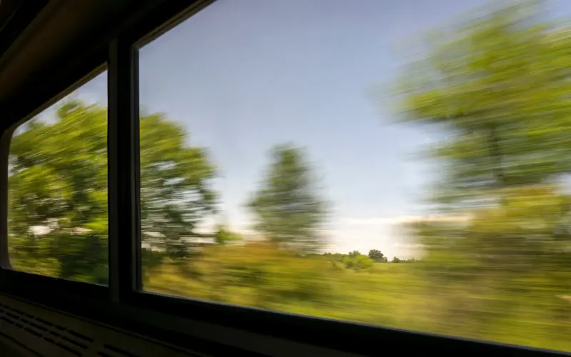 A view of green scenery from a train window - solo holiday deals