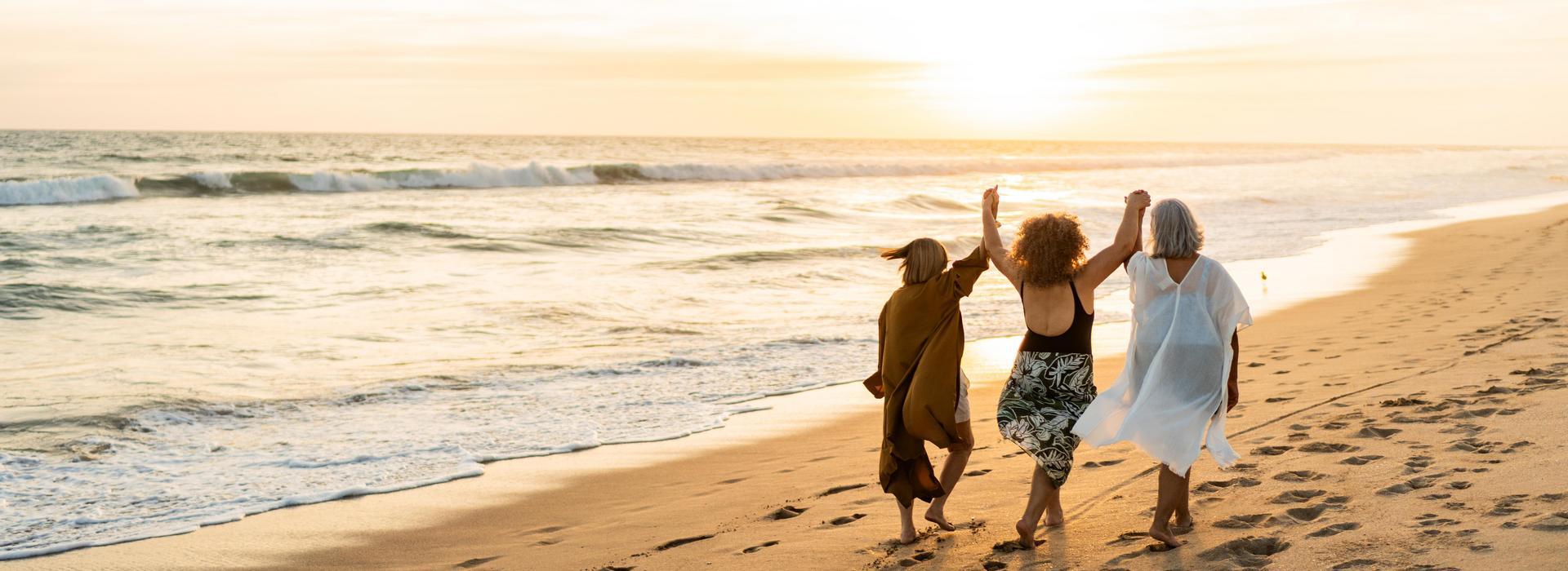 Three ladies walking on a beach as part of a solo escorted tour holiday